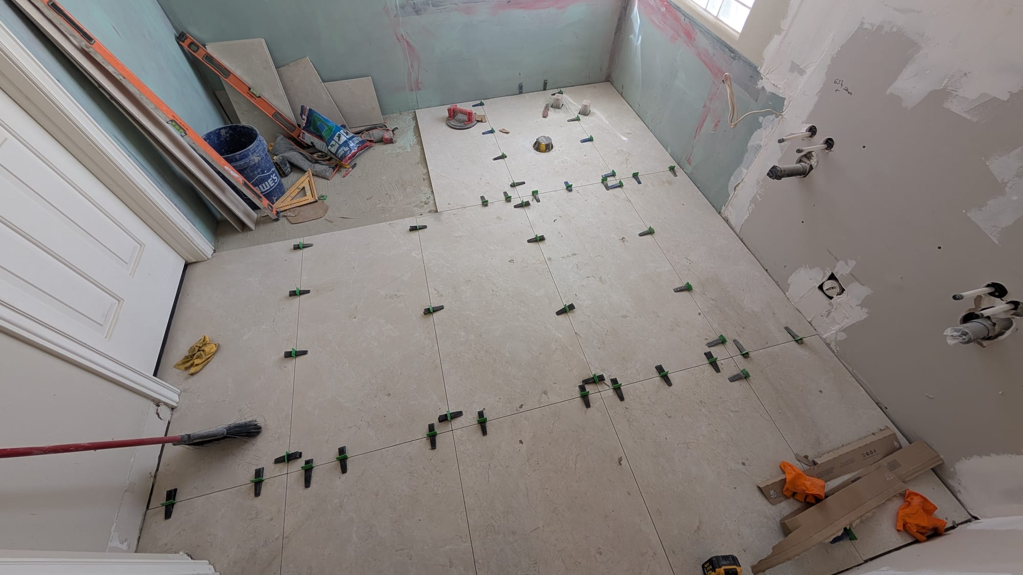 Bathroom floor tile being set with leveling clips by Haggerty Construction