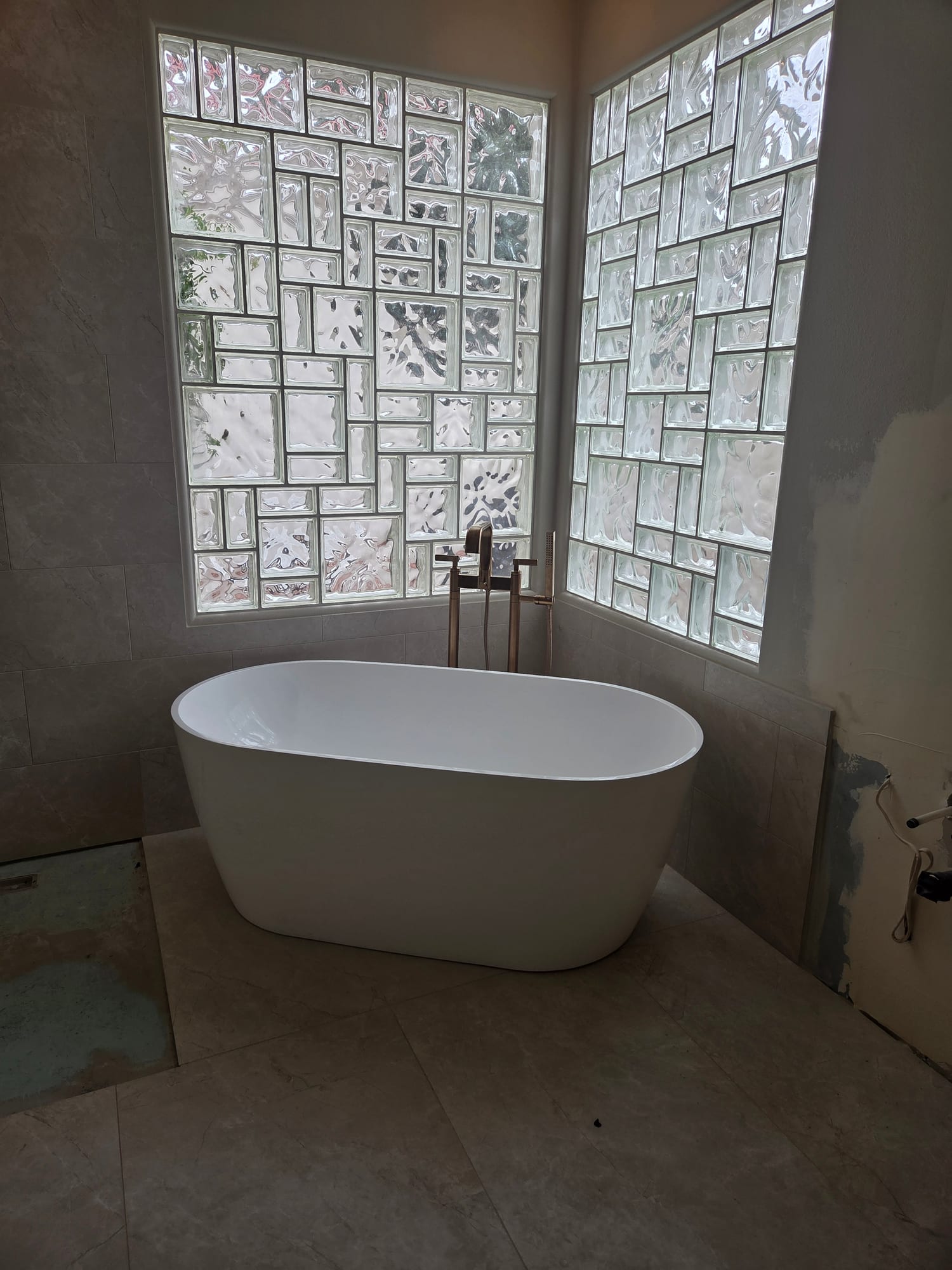 Freestanding soaking tub with glass-block windows in a Haggerty Construction master bath