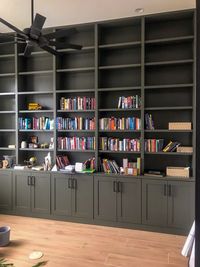 The green bookcase from the side, showing the shaker doors and the cabinet run along the floor