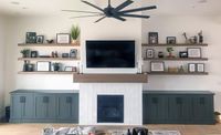 Green living room cabinets around a tile fireplace with wood floating shelves