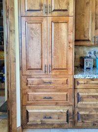 Knotty alder pantry cabinet with raised-panel doors and three drawers