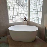 Freestanding soaking tub with gold fixtures and glass block window wall