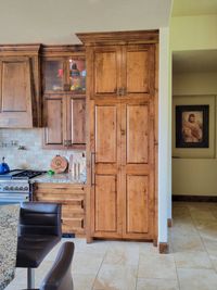 Knotty alder tall cabinet with glass-front uppers beside it in a kitchen remodel