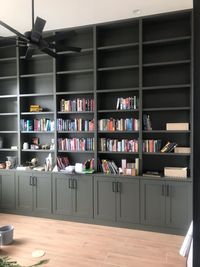 Floor-to-ceiling dark green built-in bookcase with shaker cabinet doors