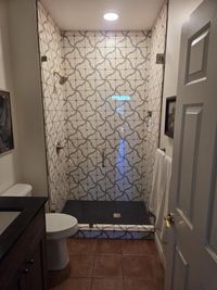 Finished guest bathroom with a patterned-tile walk-in shower by Haggerty Construction