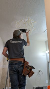 Haggerty Construction team member doing ceiling repair work in branded shirt and tool belt