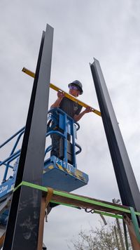Setting the steel scoreboard posts from a lift at the rink