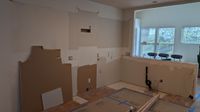 The same kitchen with the old cabinets removed and the existing tile floor covered to protect it
