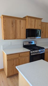 Natural oak kitchen cabinets with white quartz countertops and stainless appliances