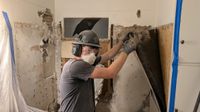 Haggerty Construction pulling old plaster and lath off a bathroom wall during a remodel