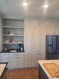 Coffee bar with open shelves on a beadboard back, beside floor-to-ceiling pantry cabinets