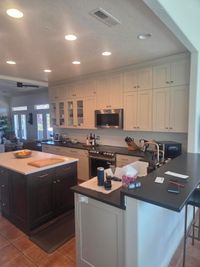 Finished kitchen with white shaker cabinets to the ceiling and a dark island