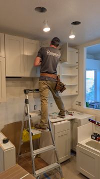 Tall white upper cabinets being installed during a whole-home remodel